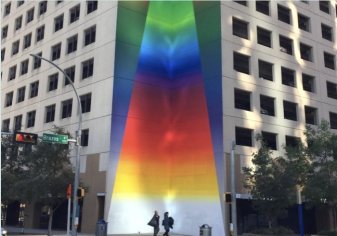 A colorful mural painted on the side of a building with two people looking up at it.